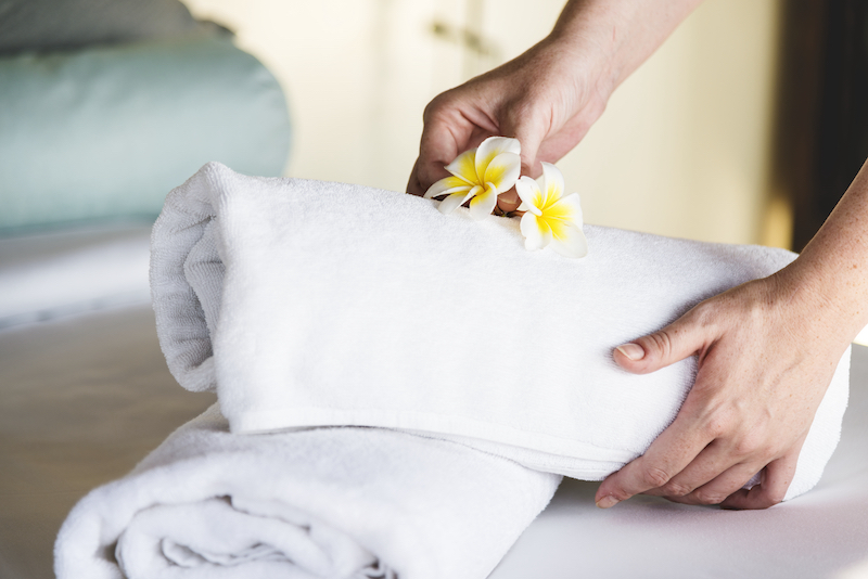 maid cleaning service placing floral array on hotel towels