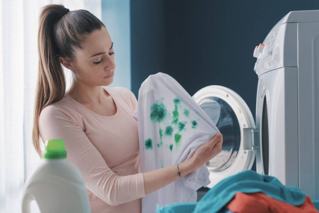 woman putting stain covered shirt in laundry