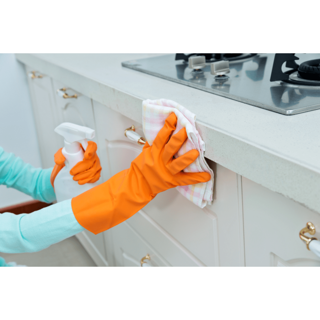 Person wearing orange gloves cleans a counter top ledge.