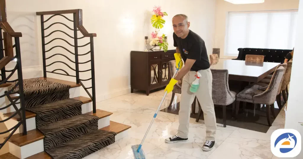 Professional house cleaner mopping the floor in a modern living room with stylish furniture and decor