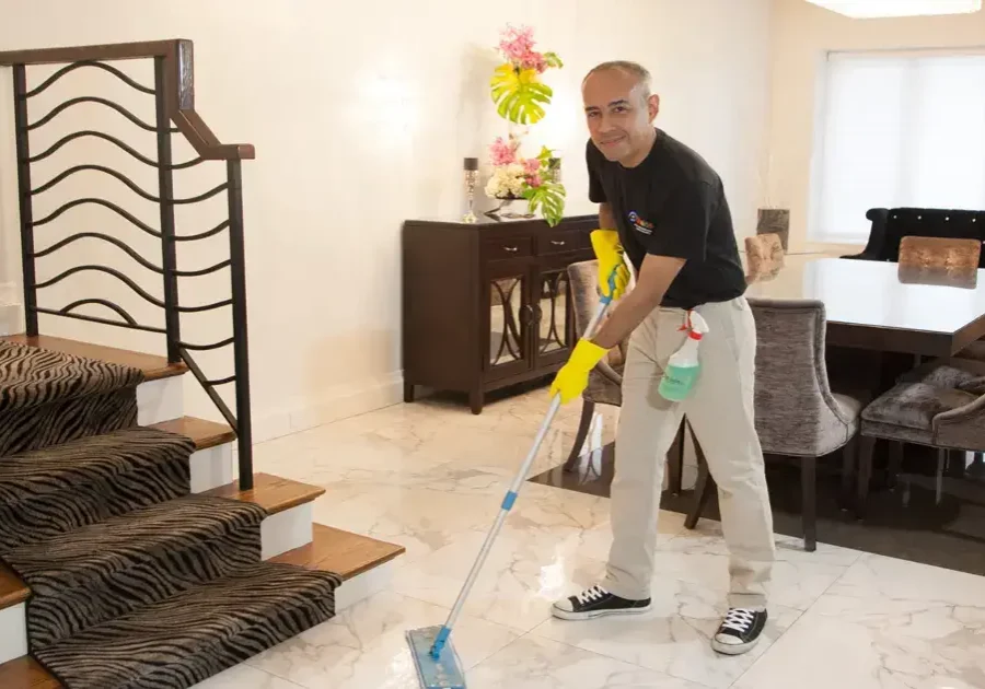 Professional house cleaner mopping the floor in a modern living room with stylish furniture and decor